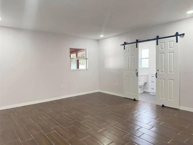 unfurnished room featuring dark hardwood / wood-style floors and a barn door