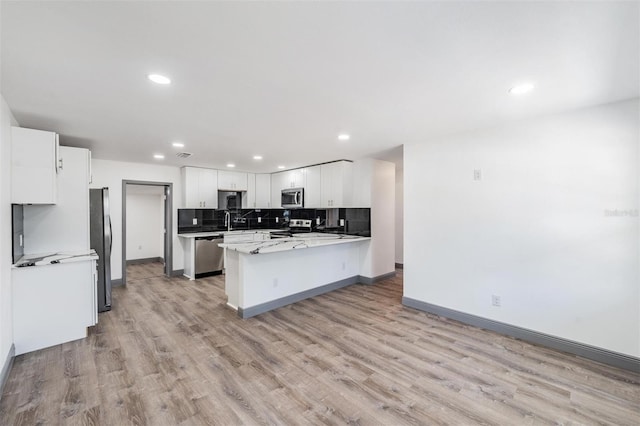 kitchen featuring stainless steel appliances, light hardwood / wood-style floors, decorative backsplash, and white cabinetry