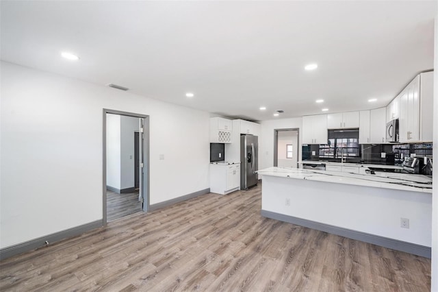 kitchen with sink, kitchen peninsula, white cabinetry, appliances with stainless steel finishes, and light wood-type flooring