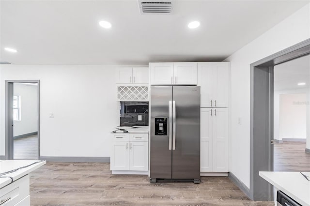 kitchen featuring stainless steel refrigerator with ice dispenser, light hardwood / wood-style floors, and white cabinetry