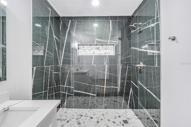 bathroom featuring tiled shower and vanity