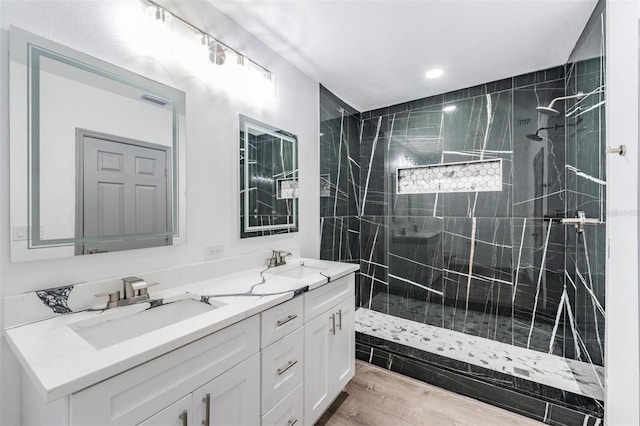 bathroom featuring wood-type flooring, a tile shower, and vanity