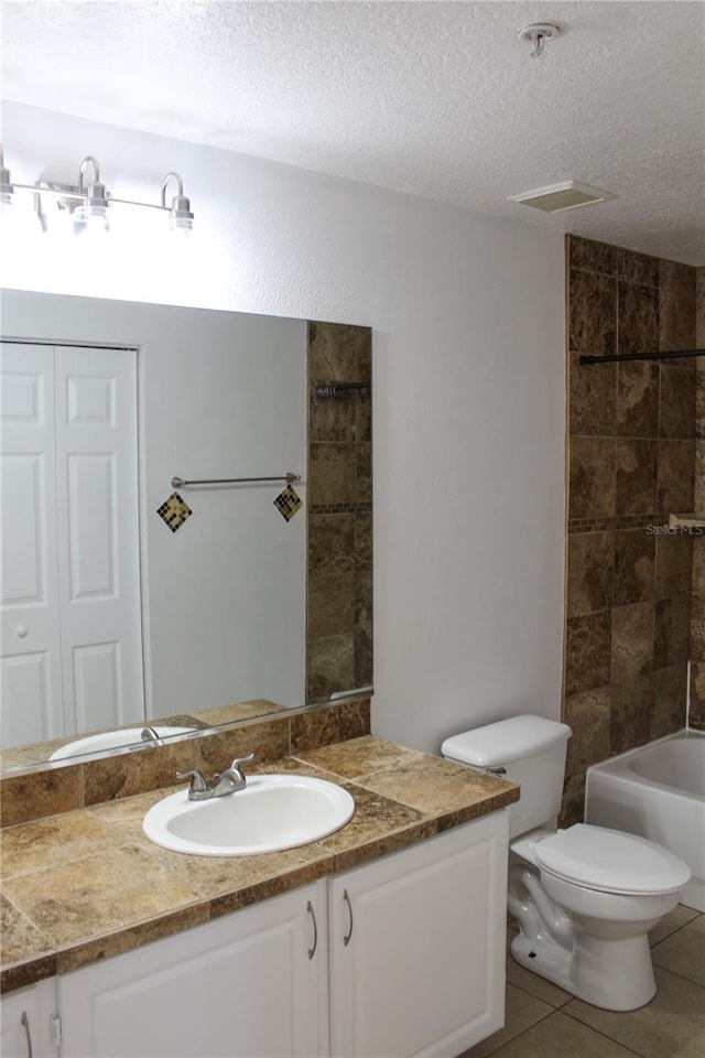 full bathroom featuring vanity, tiled shower / bath, tile patterned flooring, toilet, and a textured ceiling