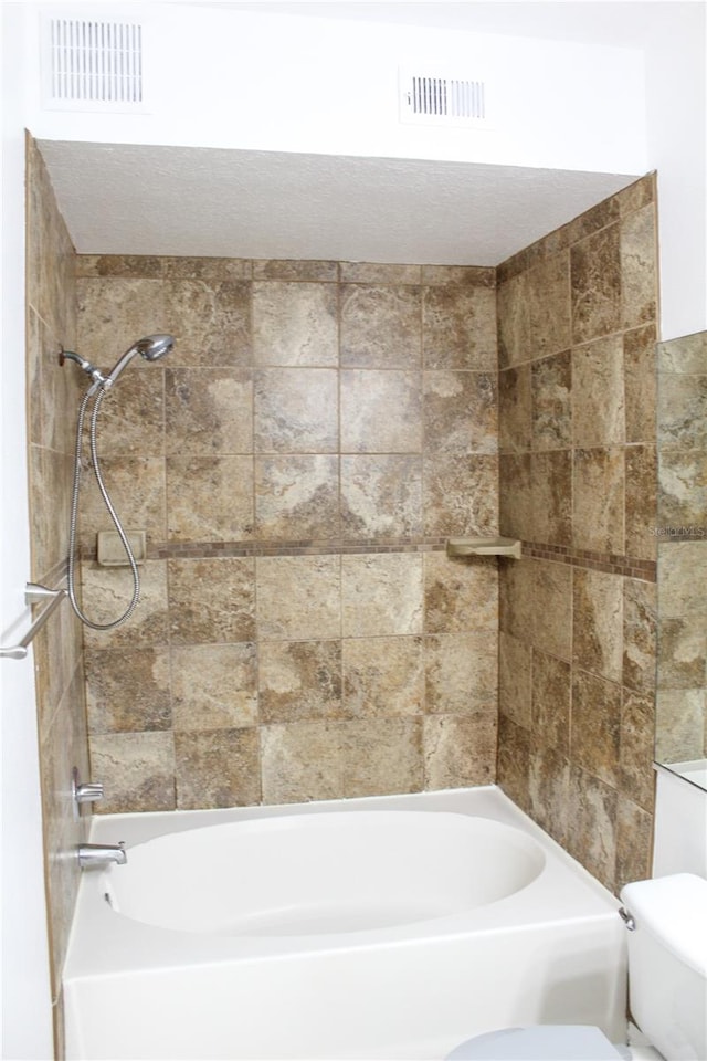 bathroom featuring toilet and tiled shower / bath