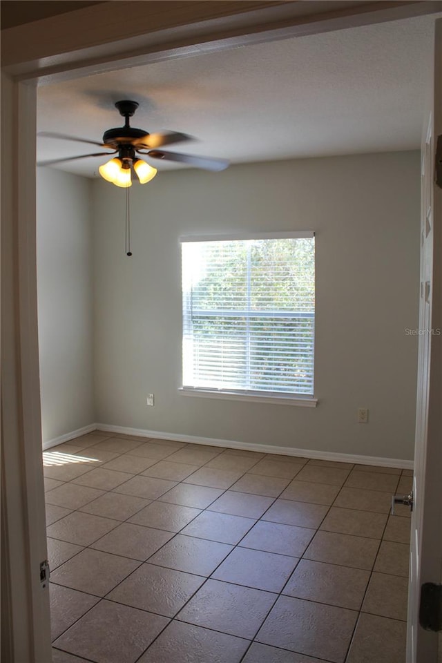 tiled spare room featuring ceiling fan