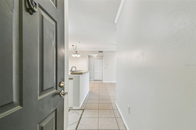 5608 Pinnacle Heights Cir Unit 305, Tampa, FL 33624 - hall featuring light tile patterned floors, ornamental molding, a chandelier, a sink, and baseboards