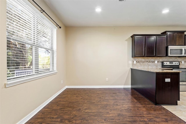 kitchen featuring backsplash, light stone countertops, stainless steel appliances, light hardwood / wood-style flooring, and dark brown cabinetry