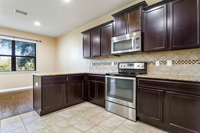 kitchen with appliances with stainless steel finishes, decorative backsplash, kitchen peninsula, light hardwood / wood-style flooring, and dark brown cabinetry