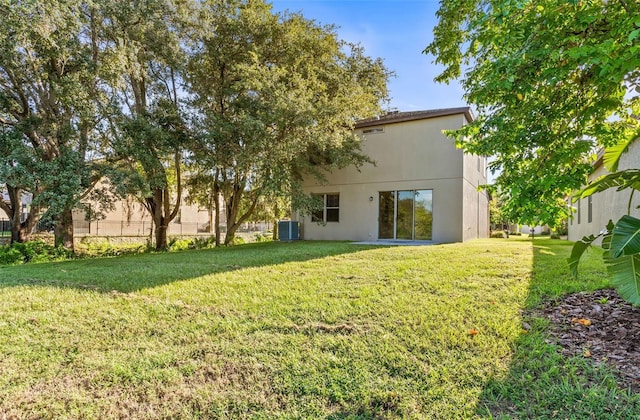 rear view of property featuring a lawn and cooling unit