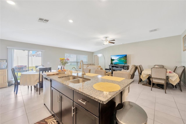 kitchen featuring an island with sink, light stone countertops, ceiling fan, stainless steel dishwasher, and sink