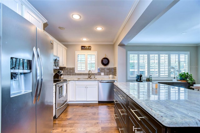 kitchen with appliances with stainless steel finishes, sink, a healthy amount of sunlight, and white cabinetry