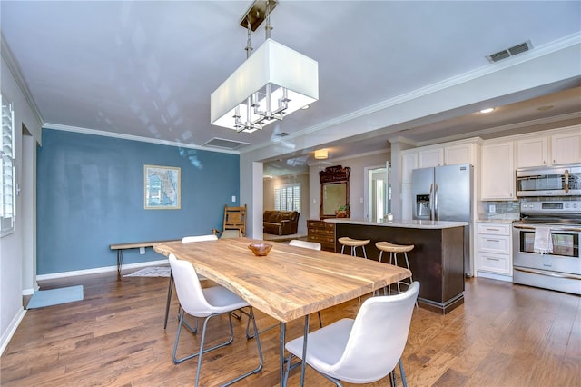 dining area with wood-type flooring, crown molding, and a chandelier