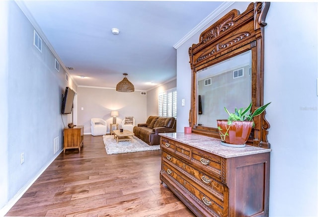 corridor with ornamental molding and hardwood / wood-style floors