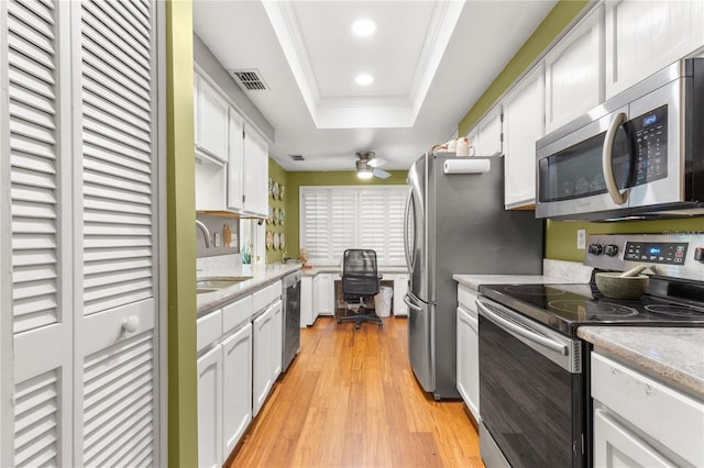 kitchen with crown molding, stainless steel appliances, a raised ceiling, and white cabinets