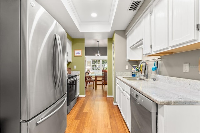 kitchen featuring sink, decorative light fixtures, appliances with stainless steel finishes, a raised ceiling, and white cabinets