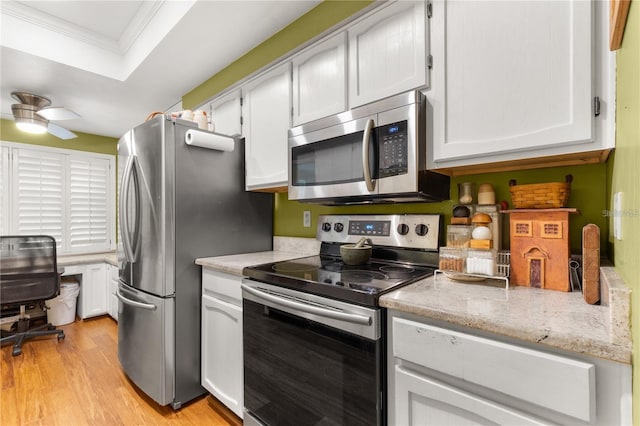 kitchen with stainless steel appliances, ornamental molding, white cabinets, and light hardwood / wood-style floors