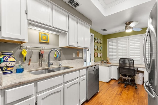 kitchen with appliances with stainless steel finishes, sink, white cabinets, ceiling fan, and light hardwood / wood-style floors