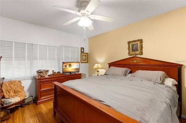 bedroom with ceiling fan, light hardwood / wood-style floors, and a textured ceiling