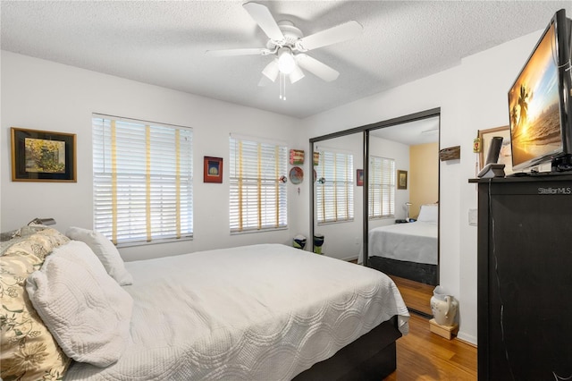 bedroom featuring ceiling fan, a closet, wood-type flooring, and a textured ceiling