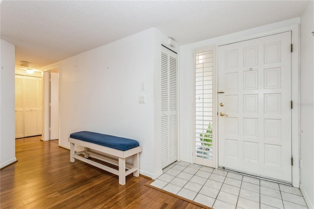 foyer entrance with a textured ceiling and light wood-type flooring