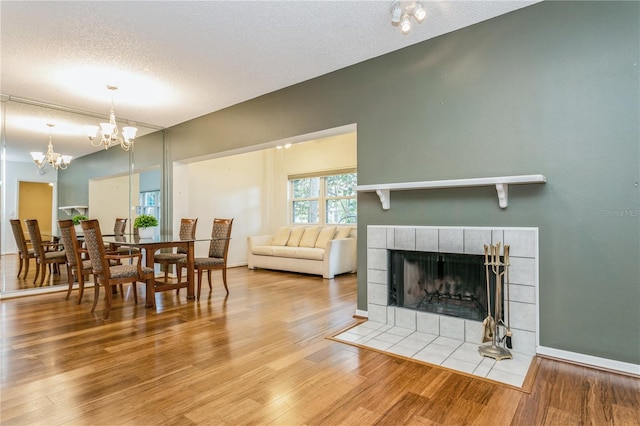 living room with an inviting chandelier, a fireplace, wood-type flooring, and a textured ceiling