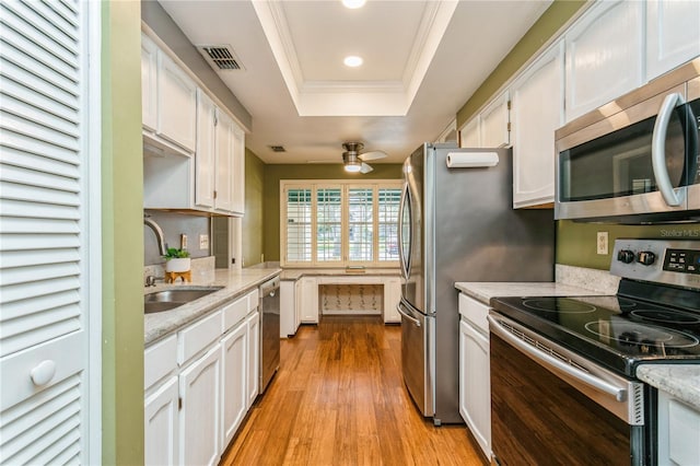 kitchen with white cabinetry, light hardwood / wood-style flooring, stainless steel appliances, and a raised ceiling