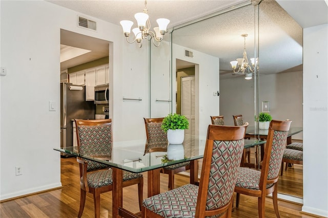 dining space with hardwood / wood-style flooring, a chandelier, and a textured ceiling