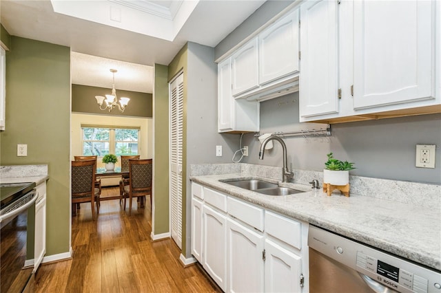 kitchen with sink, white cabinets, hanging light fixtures, stainless steel appliances, and light hardwood / wood-style flooring