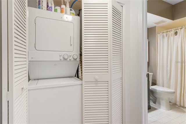 laundry area with light tile patterned floors and stacked washer / dryer