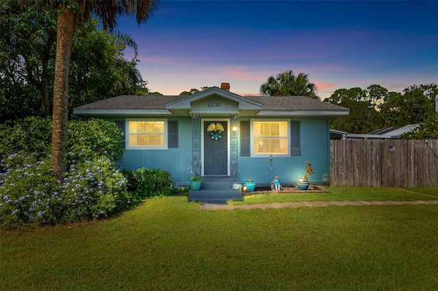 bungalow with a chimney, a front yard, and fence