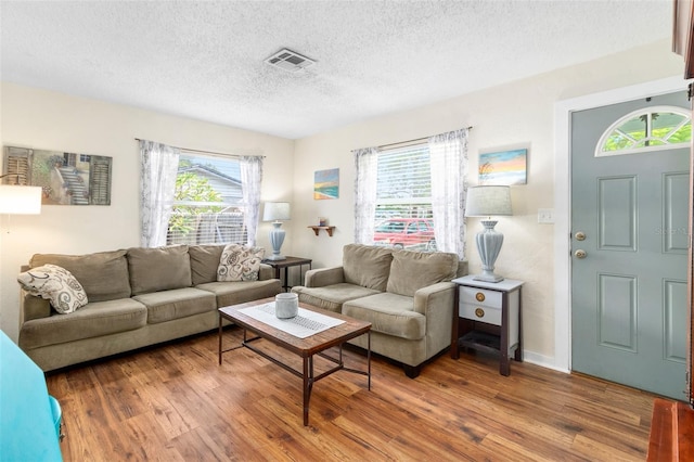 living area featuring visible vents, wood finished floors, and a textured ceiling