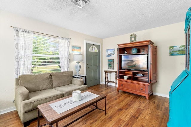 living room featuring wood finished floors, a textured ceiling, and visible vents