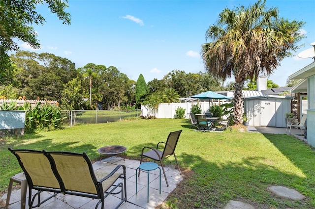 view of yard featuring a storage shed, a patio, and an outdoor fire pit