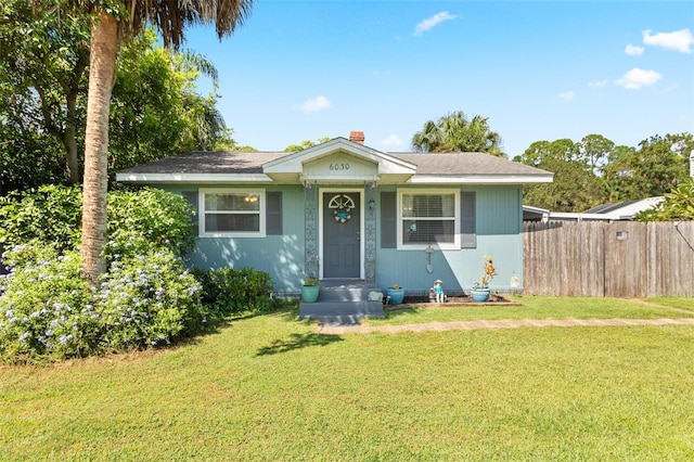 bungalow featuring a chimney, fence, and a front lawn