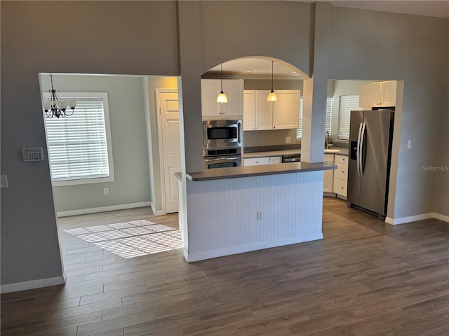 kitchen with white cabinets, pendant lighting, a chandelier, appliances with stainless steel finishes, and dark hardwood / wood-style flooring