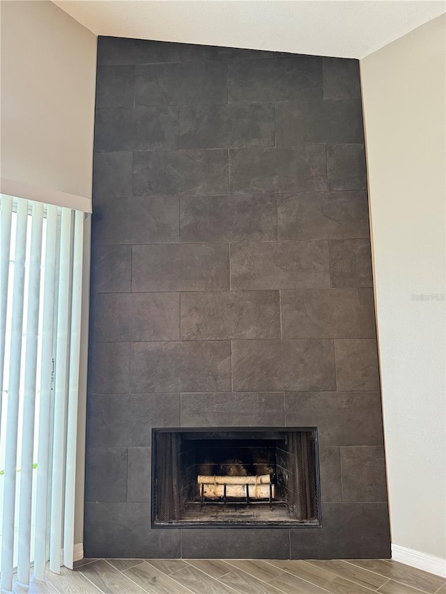 interior details featuring wood-type flooring and a tiled fireplace