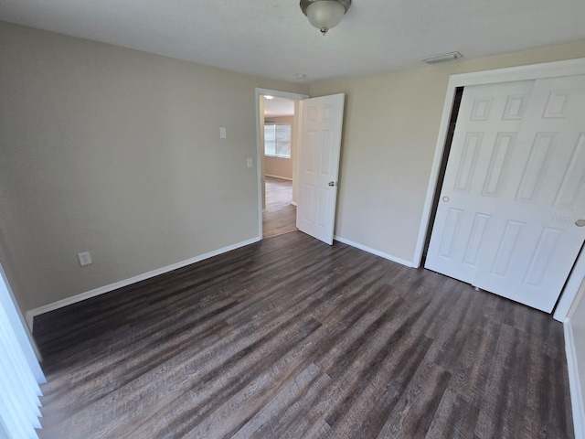 unfurnished bedroom featuring dark wood-type flooring and a closet