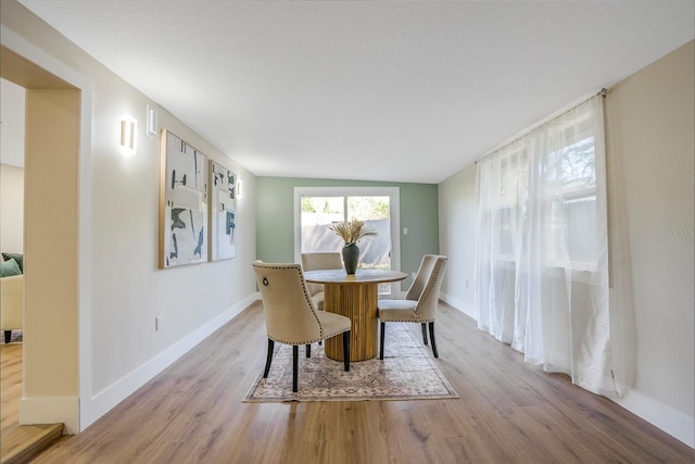 dining space with light wood-type flooring and lofted ceiling