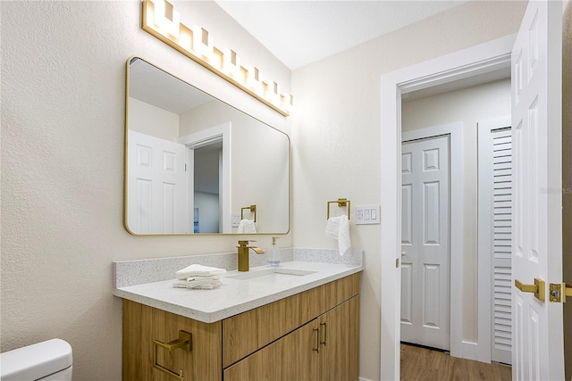 bathroom with toilet, vanity, and hardwood / wood-style floors