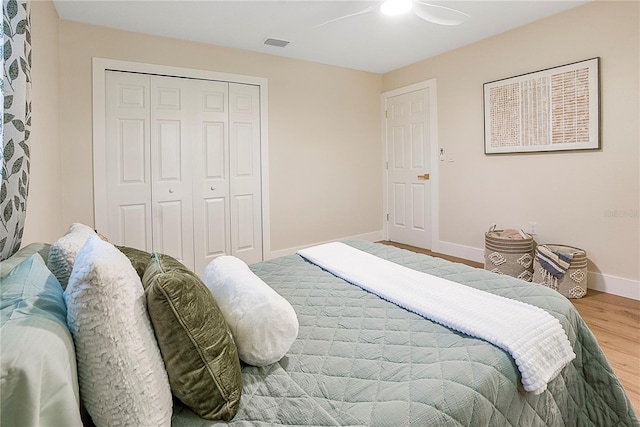 bedroom with ceiling fan, a closet, and wood-type flooring