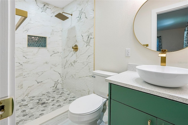 bathroom featuring toilet, vanity, and a tile shower