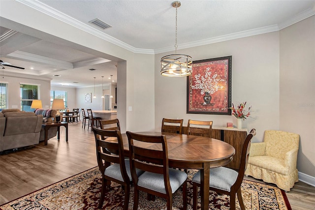 dining room featuring hardwood / wood-style flooring, beamed ceiling, a chandelier, and ornamental molding