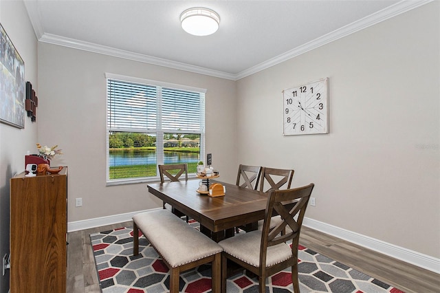 dining space featuring a water view, crown molding, baseboards, and dark wood-style flooring