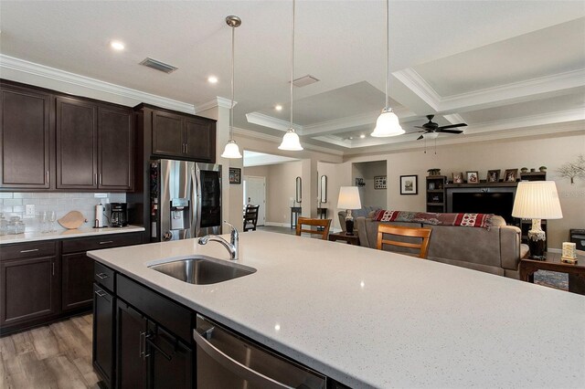 kitchen featuring pendant lighting, ornamental molding, sink, and stainless steel appliances