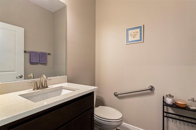 half bath featuring vanity, toilet, and baseboards