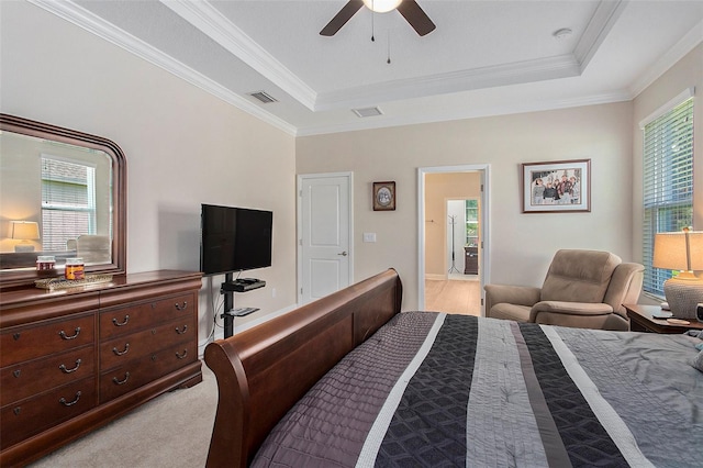 carpeted bedroom with a tray ceiling, multiple windows, ceiling fan, and crown molding