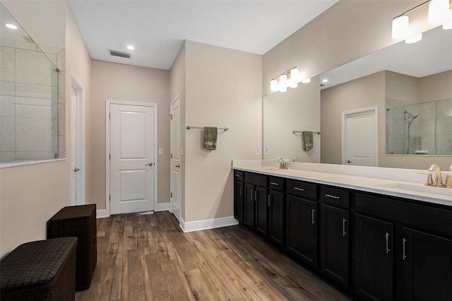 bathroom with a tile shower, vanity, and hardwood / wood-style flooring