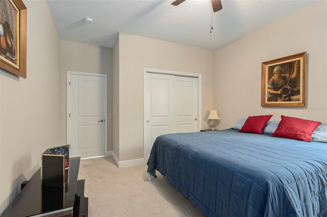 bedroom featuring light carpet, baseboards, a ceiling fan, a textured ceiling, and a closet