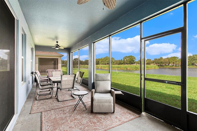 sunroom featuring ceiling fan and a water view