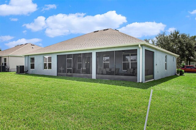 rear view of house with a sunroom, a yard, and central AC unit